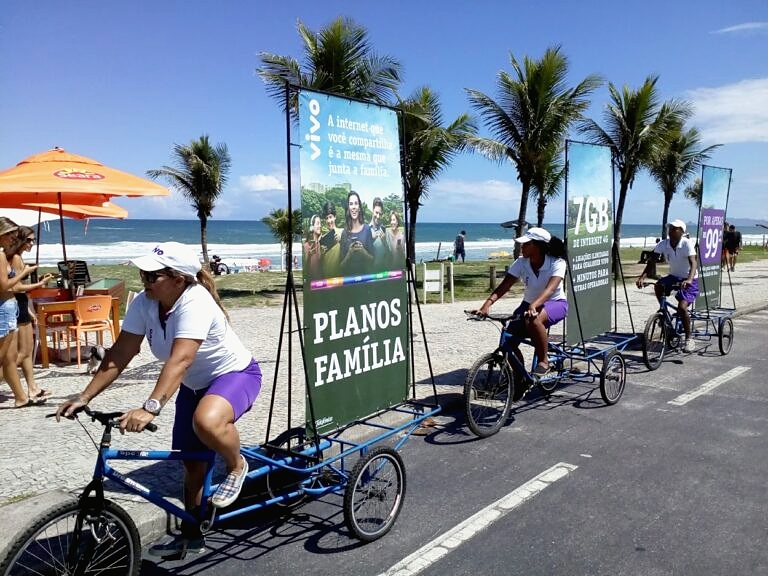 Bicicletas com painéis publicitários em circulação em via à beira-mar